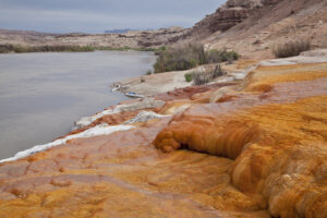 Green River at Crystal Geyser below town of Green River, Utah - a shore covered with orange mineral deposits, two kayaks