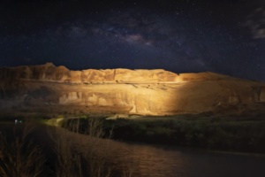 Starry night sky above the illuminated red rock canyon during the Moab Sound and Light Show