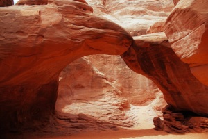 Visitors exploring Sand Dune Arch via paved pathway during Arches National Park sightseeing tour."